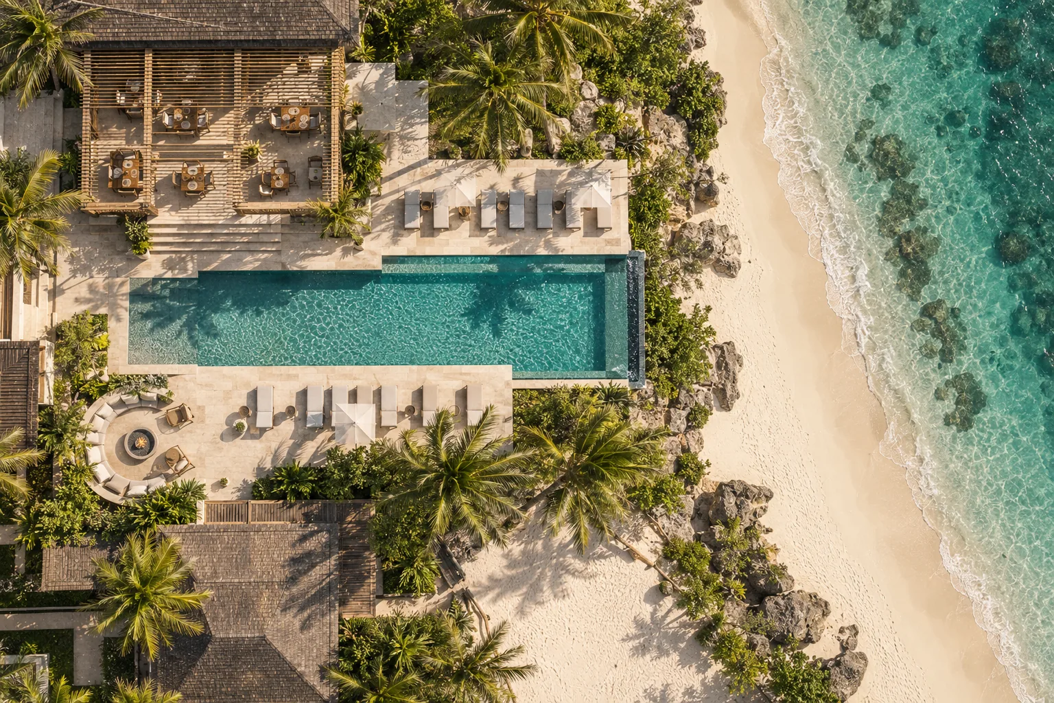 Vista aérea cenital de un resort con piscina, restaurante y fogón junto al mar